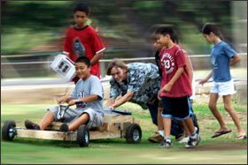 Teacher Matt Lawrence, above, and some of his 6th graders at Waikiki Elementary push a class-made battery-operated car during a show-and-tell display of their green science projects.