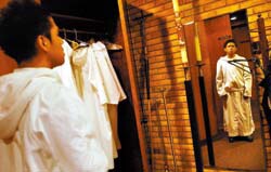 Sophomore Anthony Nguyen, below, checks his robe in the mirror in preparation for his role as acolyte in the seminary's Friday-morning Mass. Students are active in planning the Masses