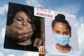 Swartz Creek resident Amy Rouleau holds up a sign that labels wearing masks as child abuse as hundreds of Genesee County residents protest against a mandatory mask mandate in schools on Wednesday, Aug. 18, 2021, outside of the Genesee County Administration Building in Flint, Mich.. The Genesee County Health Department instituted a mask mandate for K-6 students school last week.