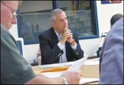 Bob Lehman, center, the superintendent of two Iowa districts serving a total of 1,300 students, attends a board meeting in the Eldora-New Providence district. He also runs a district that serves four towns, known as AGWSR.