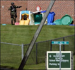 A SWAT team member checks the playground outside Essex Elementary School after a teacher was shot and killed inside the Vermont school on Aug. 24.