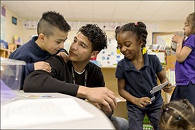 Teaching assistant Richard Nolasco listens to Joshua Flores and Ke’mari Barnes during their prekindergarten class at Tulsa’s Dual Language Academy. The population of Oklahoma’s second-largest school district has shifted dramatically in recent years, with nearly 1 in every 3 students coming from homes where Spanish is the primary language.