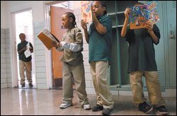 Left, Kenneth Greene leaves the restroom at Gilmor Elementary as classmates Derrick Wilhite, Juan Griffin, and Dayshawn Savage wait in line. Students are required to read during such moments so that instructional time isn't wasted.