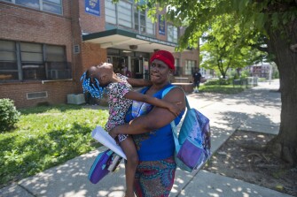 Michelle Braxton holds her daughter, Dior Braxton, 4, when picking her up during the early dismissal at Franklin Square Elementary/Middle School due to lack of air conditioning in the school building and high temperatures., Tuesday, May 31, 2022, in Baltimore, Md.