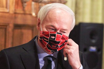 Arkansas Gov. Asa Hutchinson takes off his face mask as he arrives for a daily coronavirus briefing at the state Capitol in Little Rock, Ark. on April 27, 2020. Hutchinson signed a bill in April banning statewide and local mask mandates in Arkansas, but he is now considering rolling back that law amid concerns of the highly transmissible Delta variant of COVID-19.