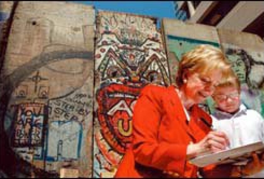 Lynne V. Cheney autographs one of her books last week in front of pieces of the Berlin Wall in an Arlington, Va., park.