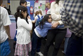 Idalis Oquendo hugs instructor Janet Medina at the after-school program at Erie Neighborhood House in Chicago. The social-services agency tutors children from the city’s school system under the No Child Left Behind Act.