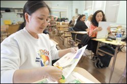 After a day teaching in the classroom, Annette Kong switches gears and clips artwork during an evening class she's taking through the Los Angeles schools to become a special education teacher.
