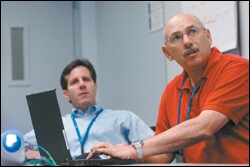 Business Savvy: Computer science teacher Allen Goodman, foreground, shows the results of a marketing survey he conducted to Russ Schafer, the director of marketing and technology management at the Intel Corp.