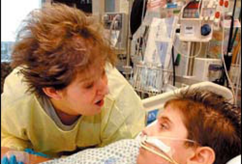Mother Kim Collins talks to her son, Nick, 9, as he opens his eyes briefly in a pediatric intensive care unit in Arkansas.