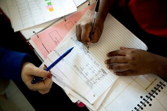 Jill Ruby, left, one of the coaches in the program that provides academic assistance at Hughes, helps senior cheerleader Randionna Wright with her homework.