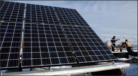 Workers install solar panels on the roof of Walden III Middle and High School in Racine, Wis., in December. Some teachers tie lessons to environmentally friendly building designs.