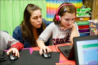 Anna Johns, right, a 2nd grader at Newnan Crossing, plays the online game as her teacher, Brandi Cook, watches. Teachers at the school are hoping the game will eventually provide them with data “dashboards” that show them how individual students are doing on a range of reading and math skills.