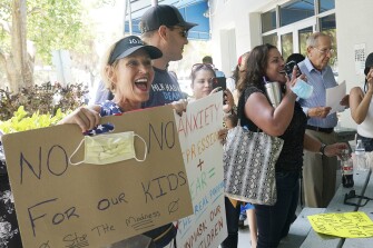 Joann Marcus of Fort Lauderdale, left, cheers as she listens to the Broward School Board's emergency meeting, Wednesday, July 28, 2021, in Fort Lauderdale, Fla. A small but vocal group spoke vehemently against masks, saying their personal rights were being eroded and their children were suffering socially.