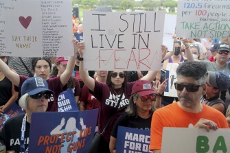 Stephanie Horowitz, 19, a recent graduate of Marjory Stoneman Douglas High School holds up a sign during the rally at Pine Trails Park Amphitheater in Parkland, Fla., on June 11.