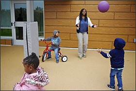 Teacher's aide Patrice Martin tosses a ball with some of the 3- and 4-year-old students at the new Educare school in Washington. Proponents are hoping the Educare approach, which combines public and private funding, will become a national model for early-childhood education.