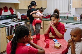 The Gantt family says grace before eating a snack at the four-bedroom townhouse they rent through the local housing authority in Tacoma, Wash.