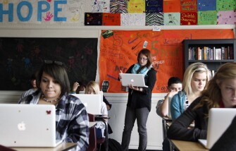 Teacher Ashley Hallmark, top, helps a freshman student log in to a test site in her communication-arts classroom at Joplin High School’s 9th and 10th grade campus in Joplin, Mo. Hallmark volunteered to search for missing students after the tornado. The Joplin school district has made one of the more rapid 1-to-1 laptop implementations in American public schooling, fueled by a $1 million-dollar donation from the United Arab Emirates.