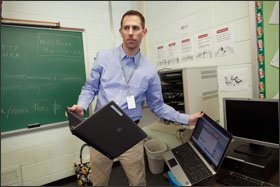 Teacher Matt Farber distributes laptops loaded with the SimCityEDU game to students at Valleyview Middle School.