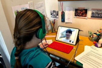 In this photo provided by Anne Marie Canlis, Clementine Canlis, of Seattle, watches an online lecture Thursday, March 12, 2020, after her private school closed for five weeks due to the coronavirus. The Canlis family’s three children, ages 14, 11 and 9, are split between two private schools that are closed for six weeks and five weeks, respectively. Canlis’ husband’s family owns a well-known, award-winning restaurant called Canlis that will close next week and instead open three different options: a bagel shop, a drive-thru burger stand in the restaurant parking lot and a home delivery meal service for cooped up families.