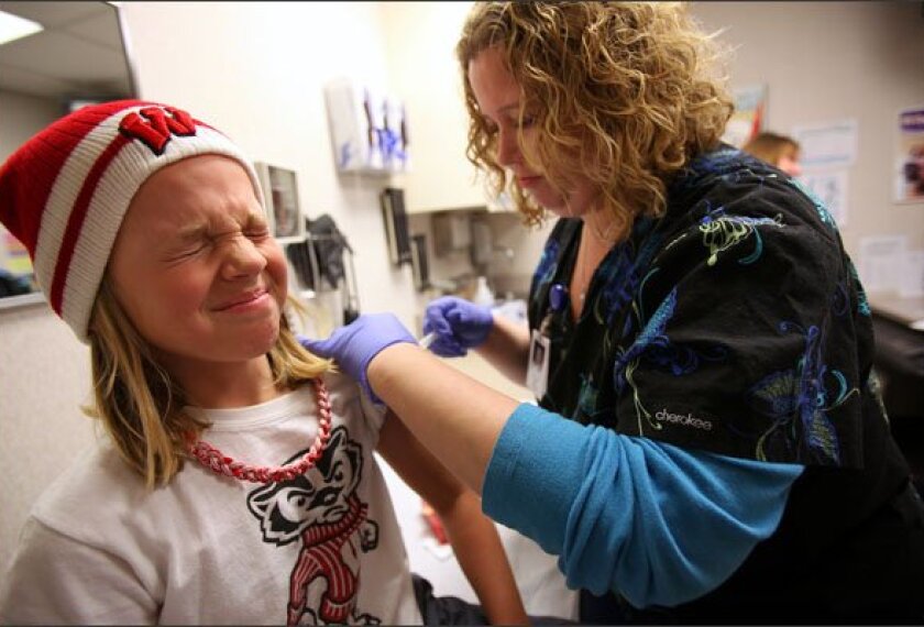 Natalie Rauwolf, 9, winces as she receives a flu shot from nurse Anna Fiore at the Dean West Clinic in Madison, Wis., this month.