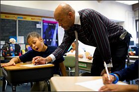 John Shelton, a 4th grade teacher, helps 11-year-old De’Jah Santiago with her math assignment at Christopher Columbus School. Teachers in Chester Upland made national news by pledging to work without pay until the district’s financial crisis could be resolved.