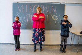 Norway’s Prime Minister Erna Solberg, center, learns a greeting technique by students Celine Busk, left and Rim Daniel Abraham, during her visit to Ellingsrudasen school in Oslo, Norway, Monday, April 27, 2020. Schools reopened for first through fourth grades in Norway after six weeks of closure, due to the coronavirus pandemic.