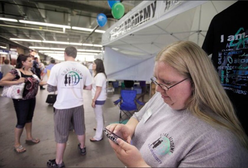 GOAL Academy academic coach April Stephen sends a text message to a student while she works at a recruiting booth for the online school, one of the state’s newest and largest online programs, at the Denver County Fair earlier this year.