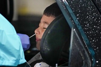 Kindergartner Iker Flores, 5, is tested for COVID-19 at a drive-through testing site in a parking garage in West Nyack, N.Y., Monday, Nov. 30, 2020. The site was only open to students and staff of Rockland County schools in an effort to test enough people to keep the schools open for in-person learning.