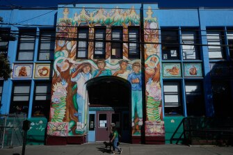 Pedestrians walk below a mural outside of César Chavez Elementary School in San Francisco, on March 18, 2026.