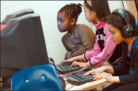 Bria, in brown, and Alexis, center, look for a word definition on a classroom computer.