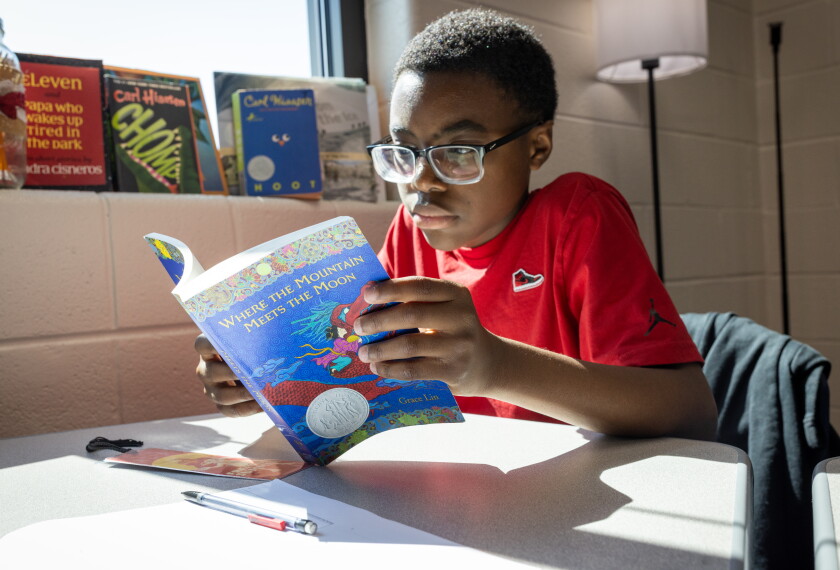 A student reads from his copy of Where the Mountain Meets the Moon at Murphy Middle School in Dacula, Ga., in teacher Jaime Johnson's 6th grade class. Johnson has students read together in class as part of an effort to ensure they complete texts and, hopefully, get hooked on the power of books.