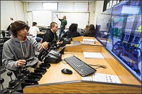 Sophomores Alex Pineda, left, and Chris Bacon, center, use simulators to learn how to operate a forklift and a tractor trailer in a class in the transportation, distribution, and logistics academy at Bryan High School.