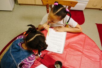 Kimora Gantt, right, shushes her younger sister, 3-year-old Brooklyn Gantt, left, while doing homework at their four bedroom townhouse. The program that helped supply the housing is one of a small but growing number of “place based” solutions that aim to tackle the problem of family mobility.