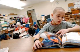 Javier Rivera, 8, concentrates on independent reading as his teacher, Marti Galvin, works with a younger group of students in the lower-elementary class for 6- to 9-year-olds. Montessori’s method encourages children to explore their interests and learn at their own pace.