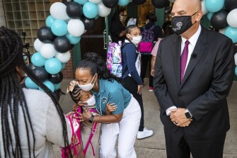 Principal Andrea Harper hugs a student as Harper and Superintendent Kent P. Scribner greet students on the first day of school Monday, Aug. 16, 2021, at T.A. Sims Elementary School in Fort Worth, Texas.