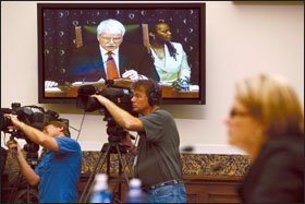 Rep. George Miller, on TV screen, addresses Secretary of Education Margaret Spellings, right, at a House education committee hearing on the Reading First program and student loans.