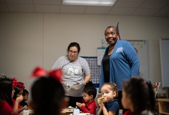 Wiggins speaks with pre-K students and staff during a lunch break at Garden Oaks Montessori in Houston, where young students eat family-style lunch in their classrooms as part of a pilot program.