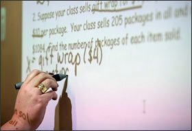 Special education teacher Lindsey L. Taylor writes on an interactive whiteboard. Taylor co-teaches a 9th grade special education course in applied science at Ashbrook High School in Gastonia, N.C.