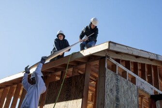 Sixteen-year-old sophomores Rodney Arnold, from left to right, Micaiah Rice and Caleb Caraker lifty plywood onto the roof of a tiny house on Friday, March 22, 2019 at Battle High School in Columbia, Mo. Students in a combined construction and geometry class are building a tiny house for a low-income family in the community.