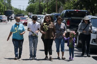People walk with flowers to honor the victims in Tuesday's shooting at Robb Elementary School in Uvalde, Texas.