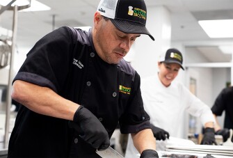 Urban cuts barbecue ribs at Fisher Middle School in Greenville, S.C. He has added ribs, fresh-caught salmon, and salad bars as part of the standard school lunch rotation.