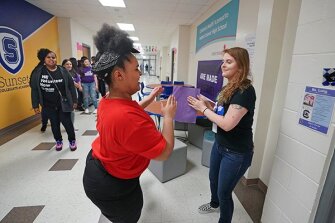 Student Honestie Sadler, in red, dances with English teacher Helen Long, as Long greets her and other students at the doorway of her classroom at Sunset High School in Dallas.