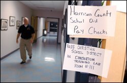 A sign alerts employees about picking up their checks at school district headquarters in Gulfport, Miss. Many teachers who fled their communities awaited word about how they would get paid.