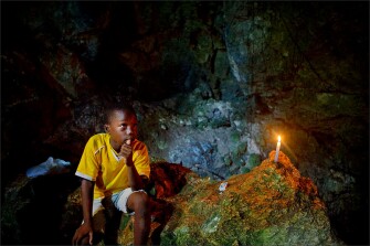 A single candle lights a young boy in a cave in the El Choco National Park near Cabarete, Dominican Republic.
