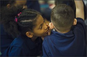 Kindergartner Yohanna Tesfamariam whispers into her classmate’s ear during a vocabulary lesson at Center City school.