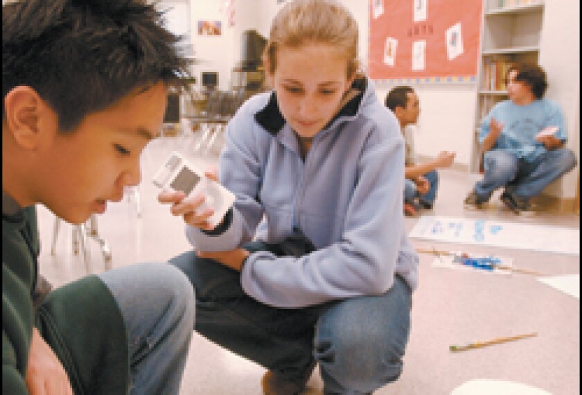 Using an iPod, 8th grader Elizabeth O'Neil records an interview with classmate Davis Tran as he works on the set design for a play at Gunston Middle School.
