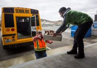 Ileana Koons, right, hands Jorge Rodriguez, left, a container of meals to be delivered to students on March 12, 2020 in Bothell, Wash. As schools across the U.S. close their doors to try to prevent the spread of the coronavirus, some are scrambling to keep meals going for millions of students who need them.