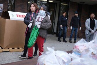 Maria Ochoa and Selvin Jimenez, 10, pick up food at a distribution point in New Rochelle, N.Y., Thursday, March 12, 2020. State officials have set up a “containment area” in the New York City suburb, where schools and houses of worship are closed within a 1-mile radius of a point near a synagogue where a person with coronavirus had attended events.