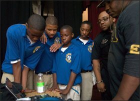 Mentor Morkeith Phillips, a Southern University at New Orleans student, right, and Jason Lewisa, a New Orleans Police Department officer, second from right, watch a step routine by the Alpha Phi Alpha fraternity on a laptop during the afterschool program.
